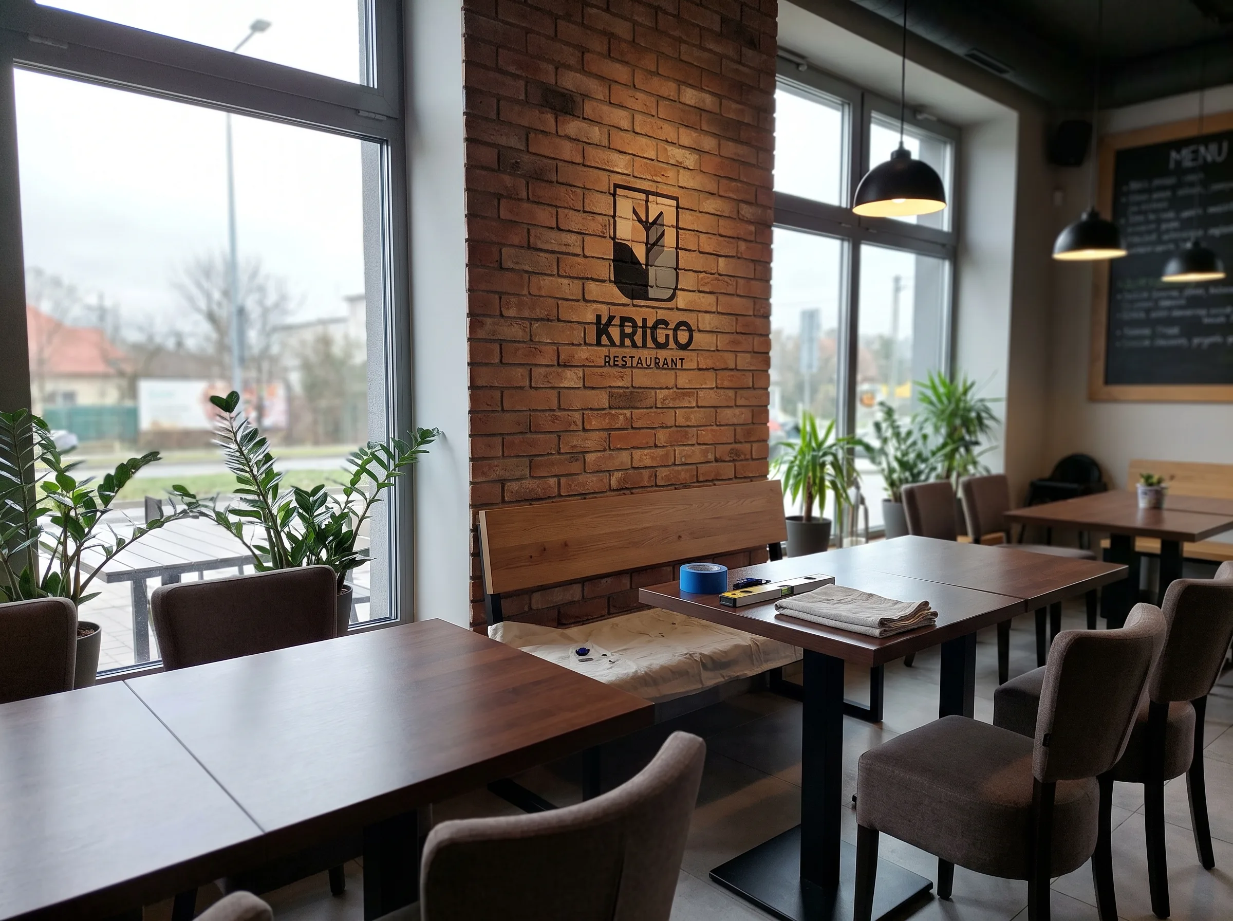 Logo restauracji KRIGO na ściennej dekoracji z cegły