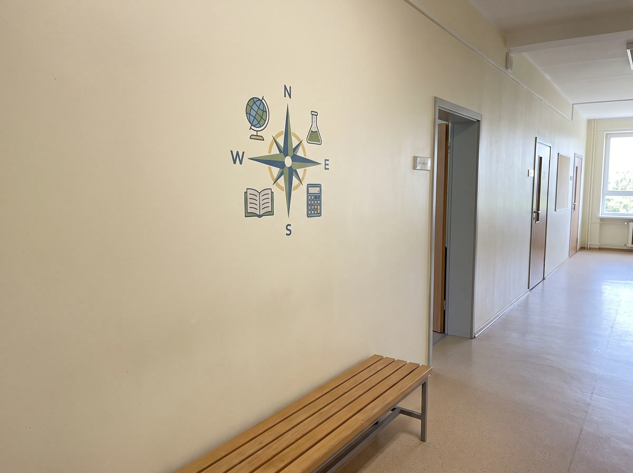 Grafika na ścianie przedstawiająca kompas z symbolami nauki w korytarzu szkoły